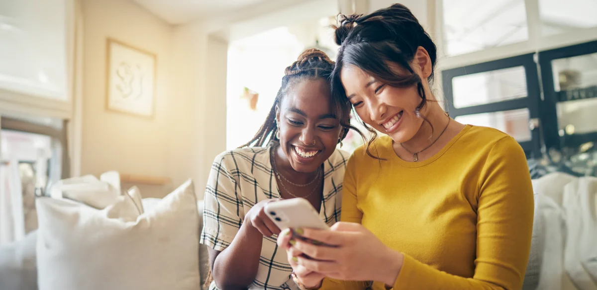 Two students smiling and looking at their cellphone